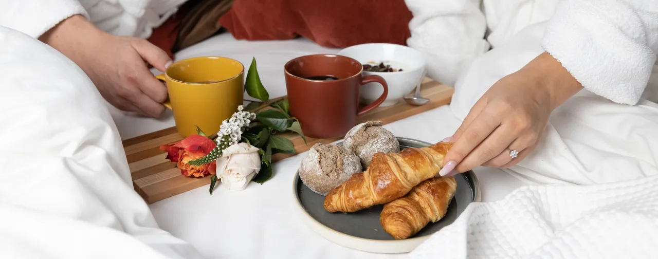 Bröllopspar äter frukost i sängen iklädda morgonrockar.