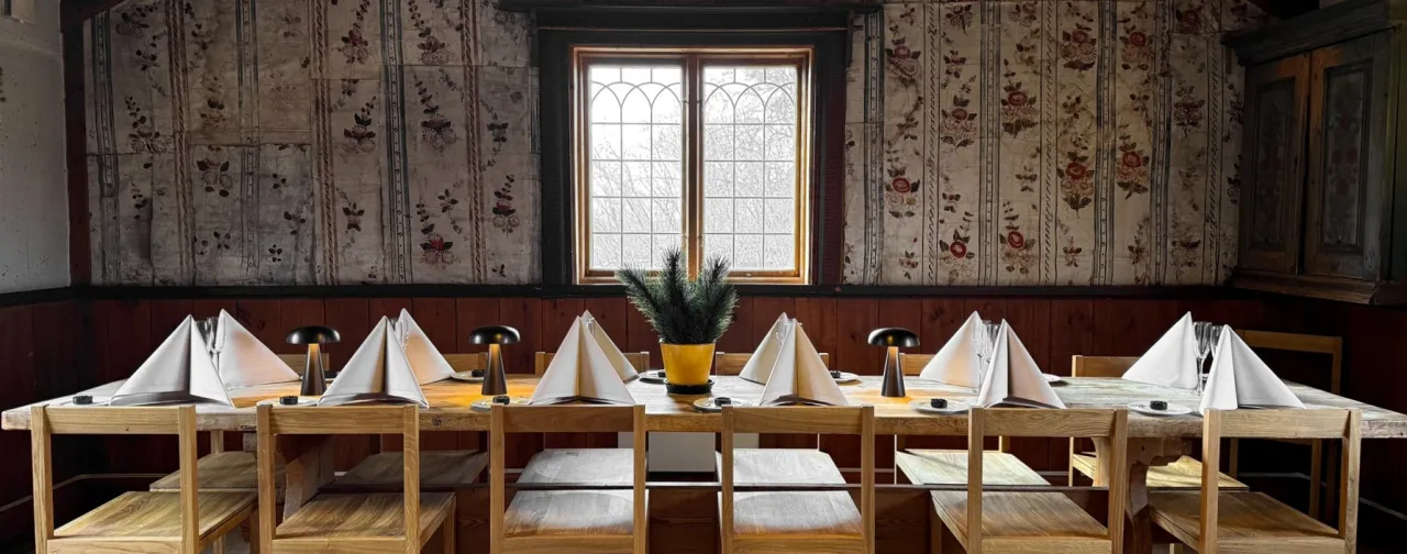 Uppdukat bord i rum med dalmålningar på väggen.