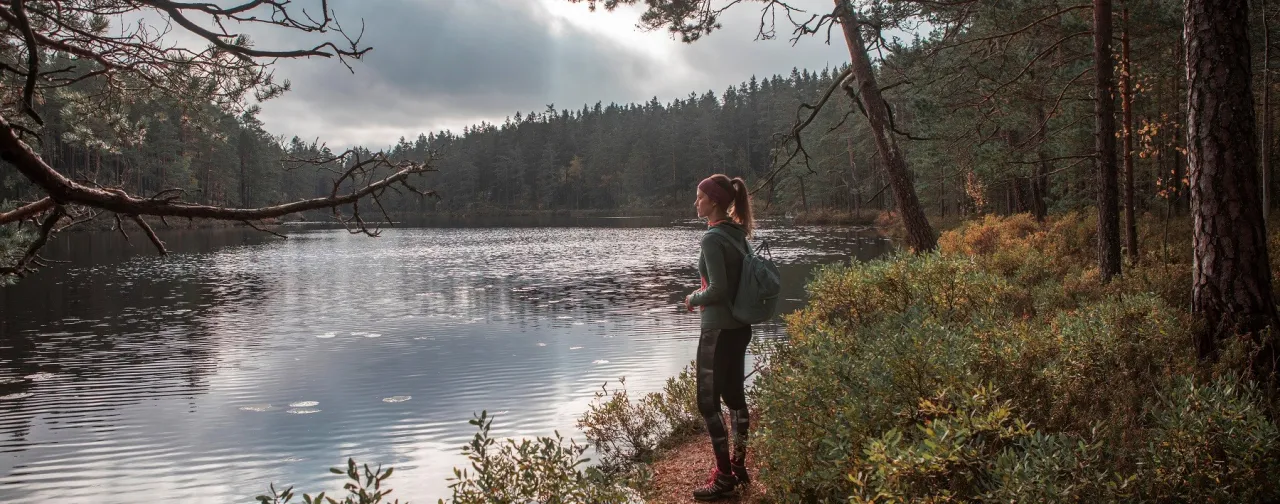 Kvinna vandrar vid en sjö.