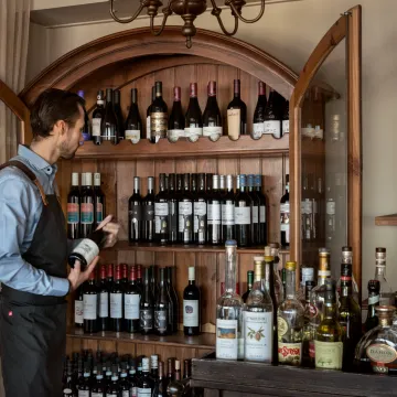 Servitör framför ett vinskåp i restaurangen på Villa Långbers. 