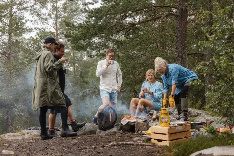 Grupp personer lagar mat i skogen.